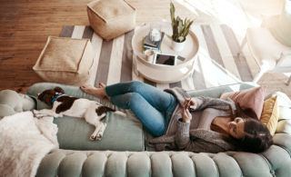 Shot of an attractive young woman using her cellphone while relaxing at home