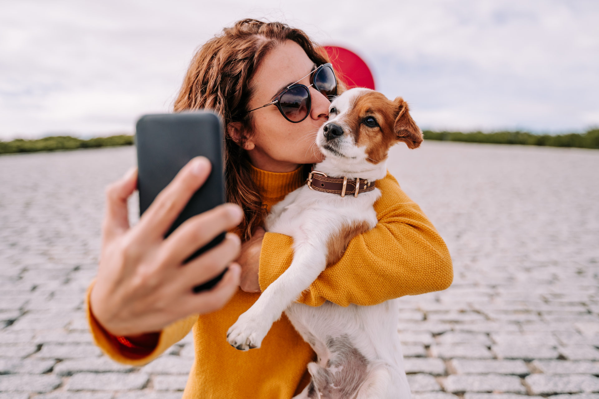 Woman kissing her pet while taking a selfie
