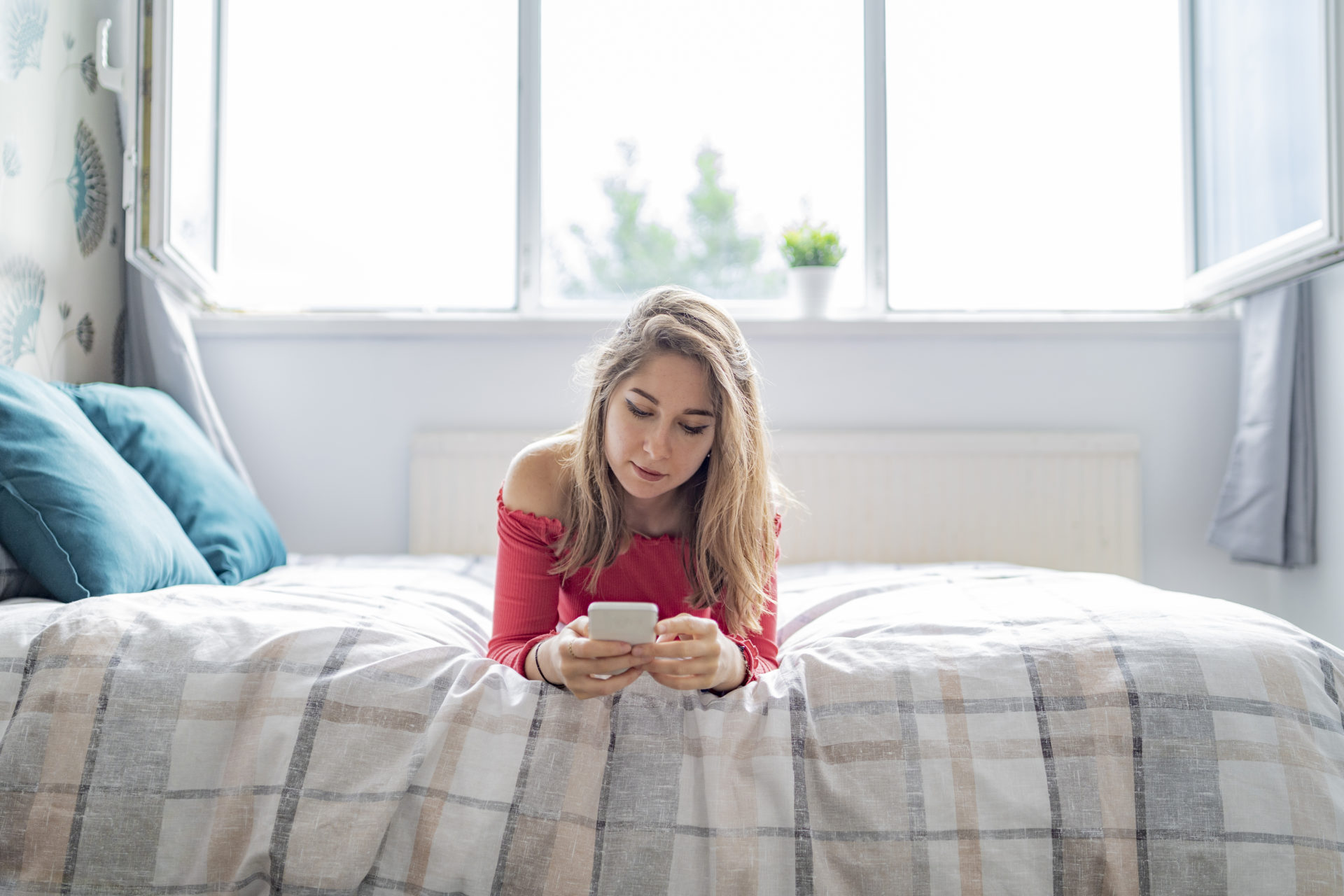 single woman looking at online dating profiles on her phone in bed