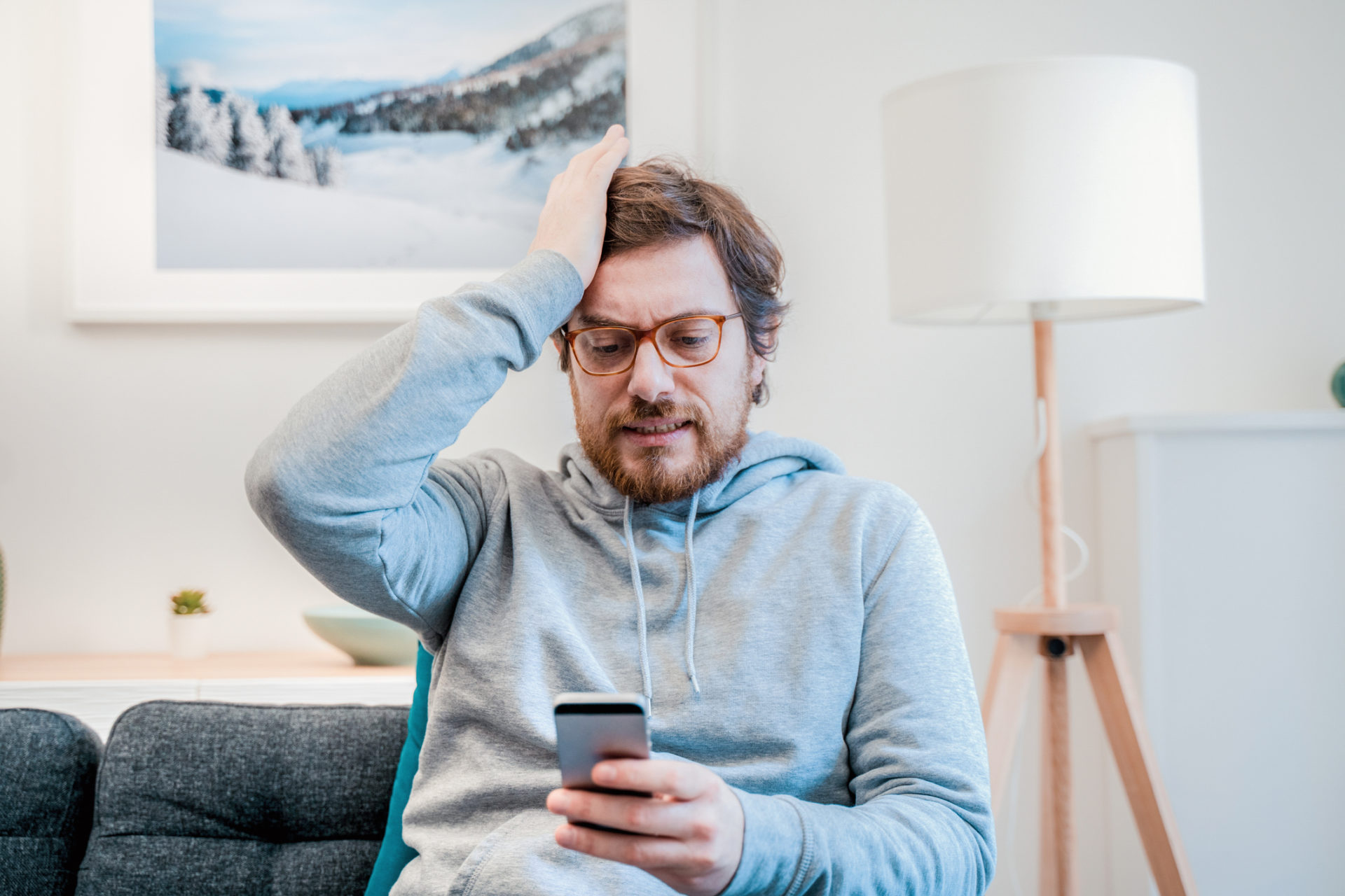 man looking at phone regretting a text message