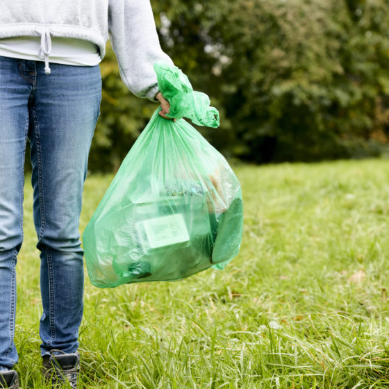 Woman tossing out the trash walking across grass